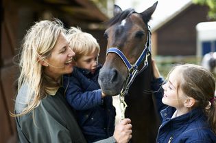 Mature woman with son and daughter petting horse