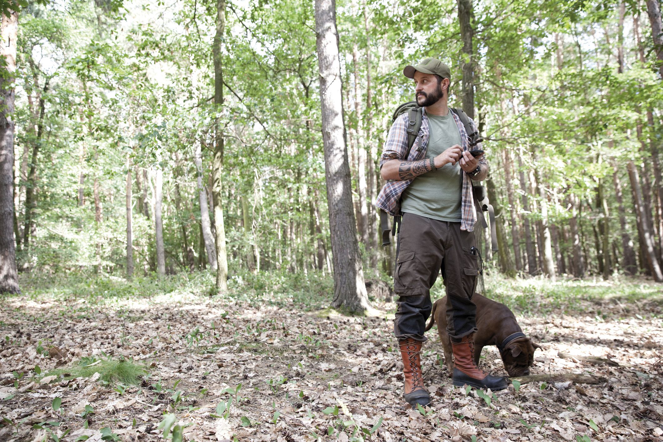 Man with cell phone and dog in the woods