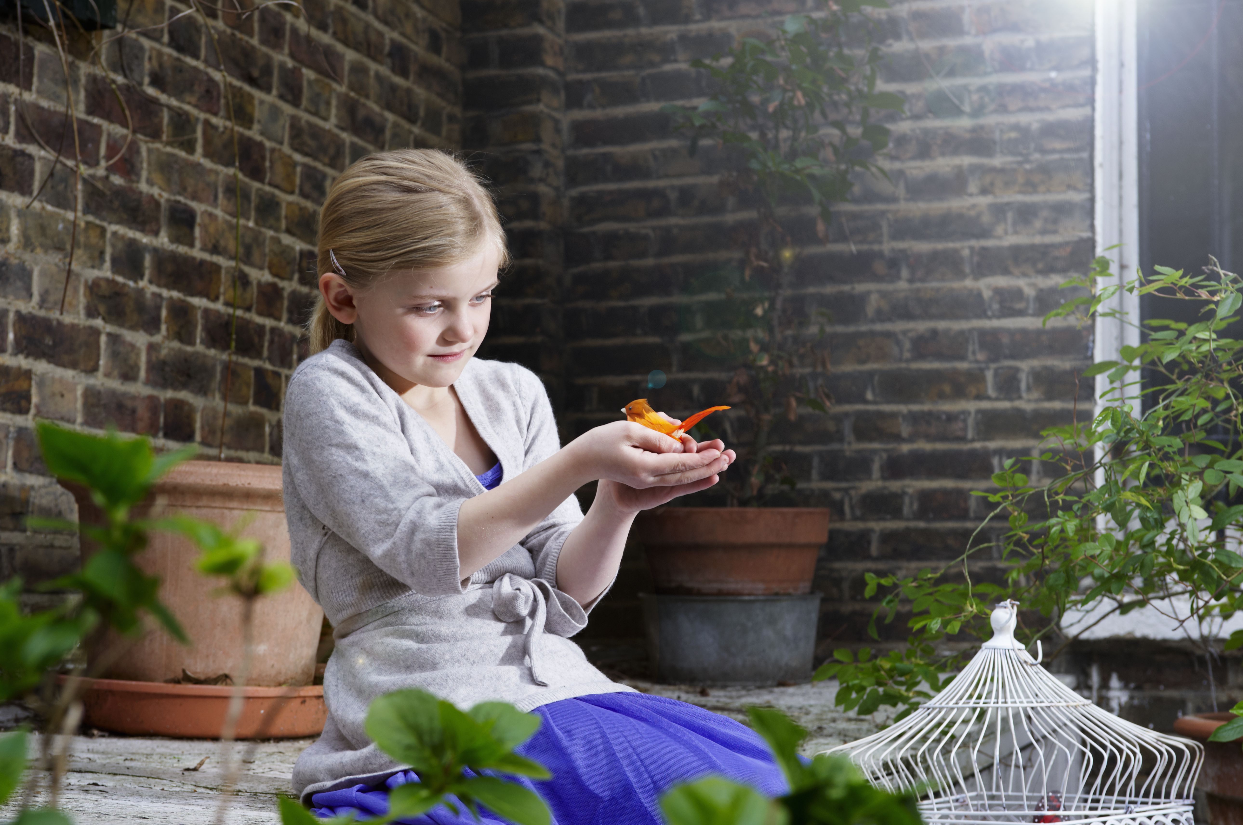 girl holding bird near bird cage