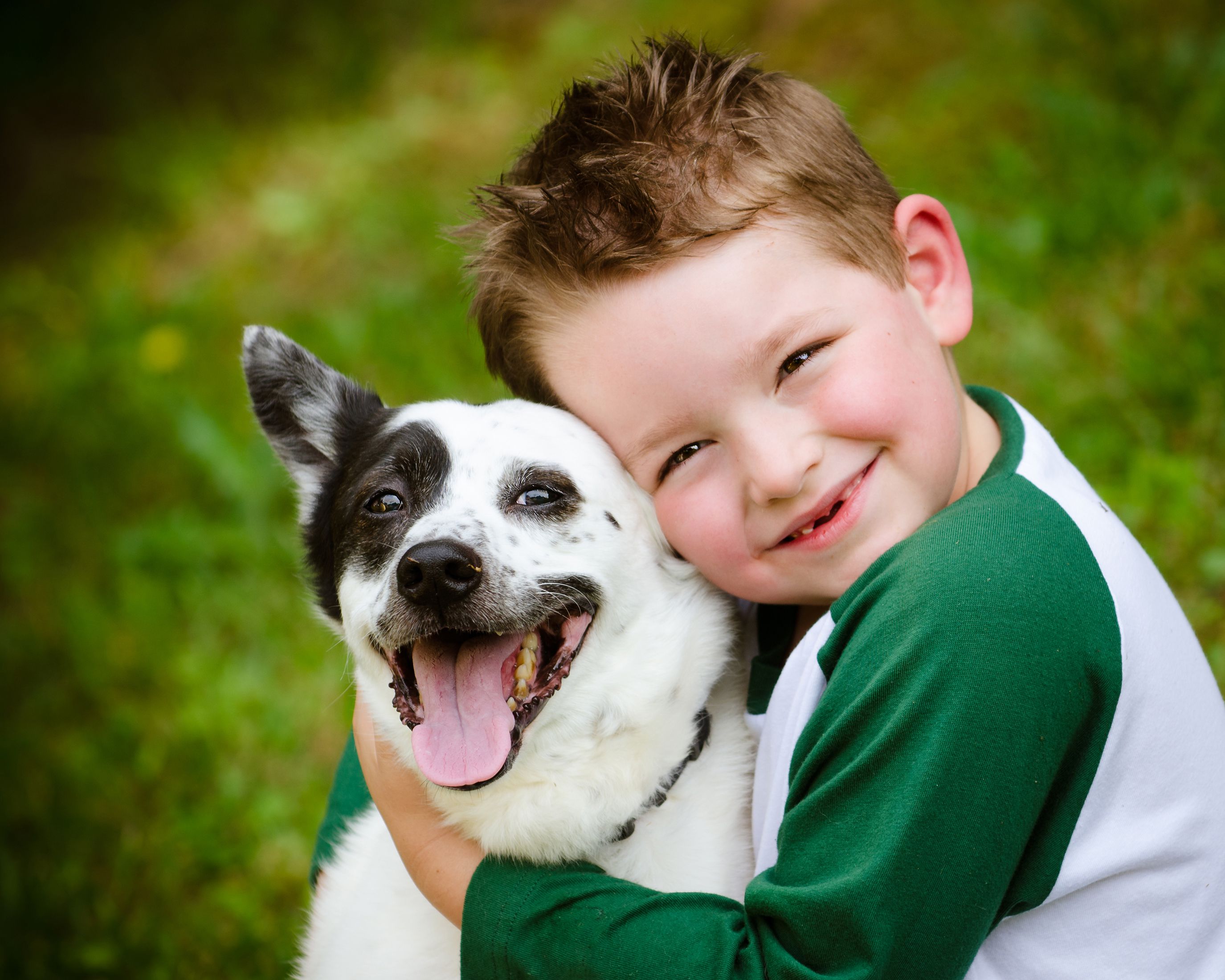 Young boy hugging happy dog with spots