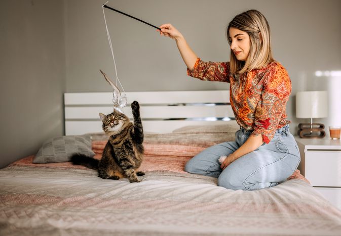woman playing with her cat for exercise