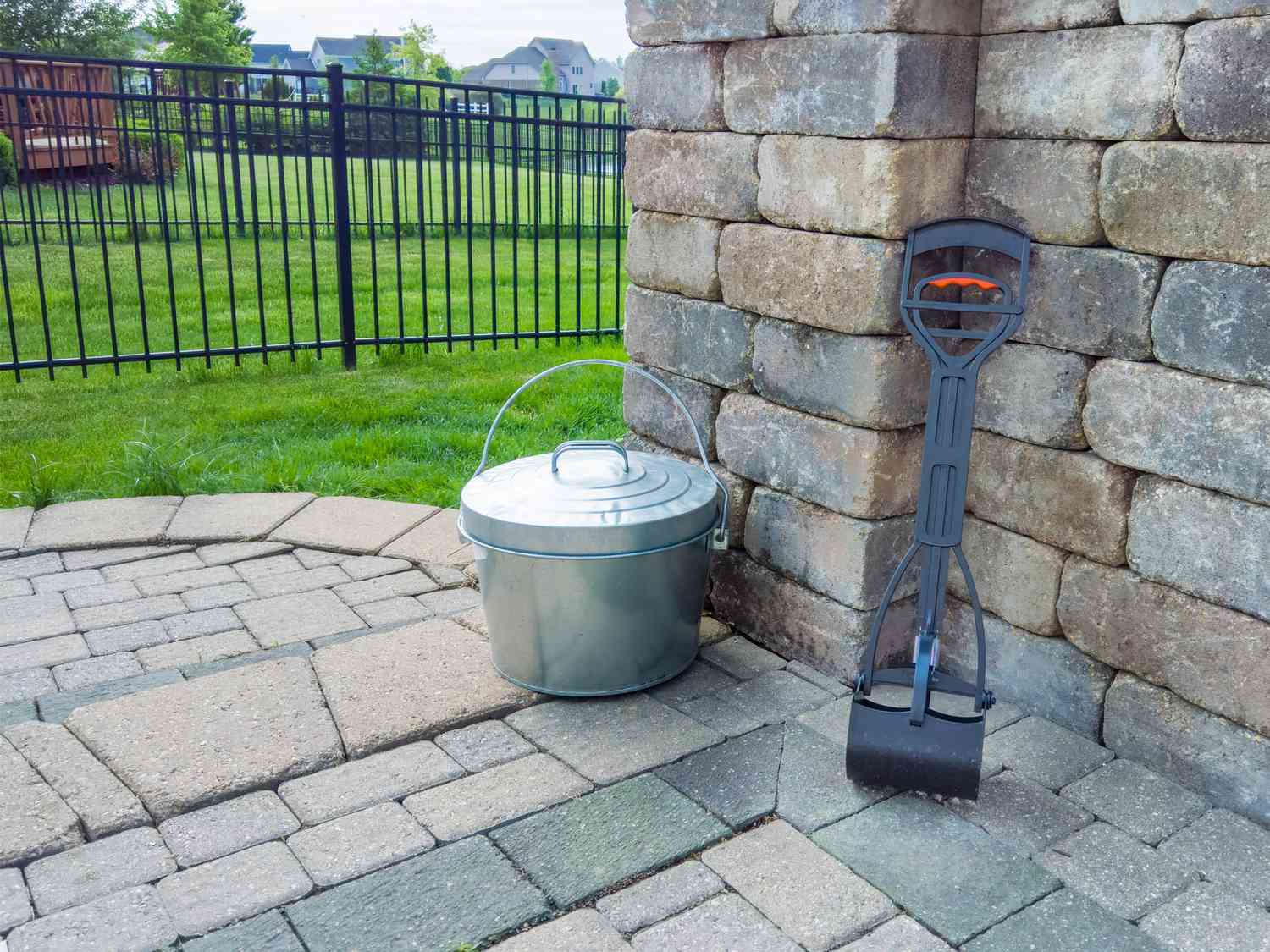 Pooper scooper next to small trash can in backyard.